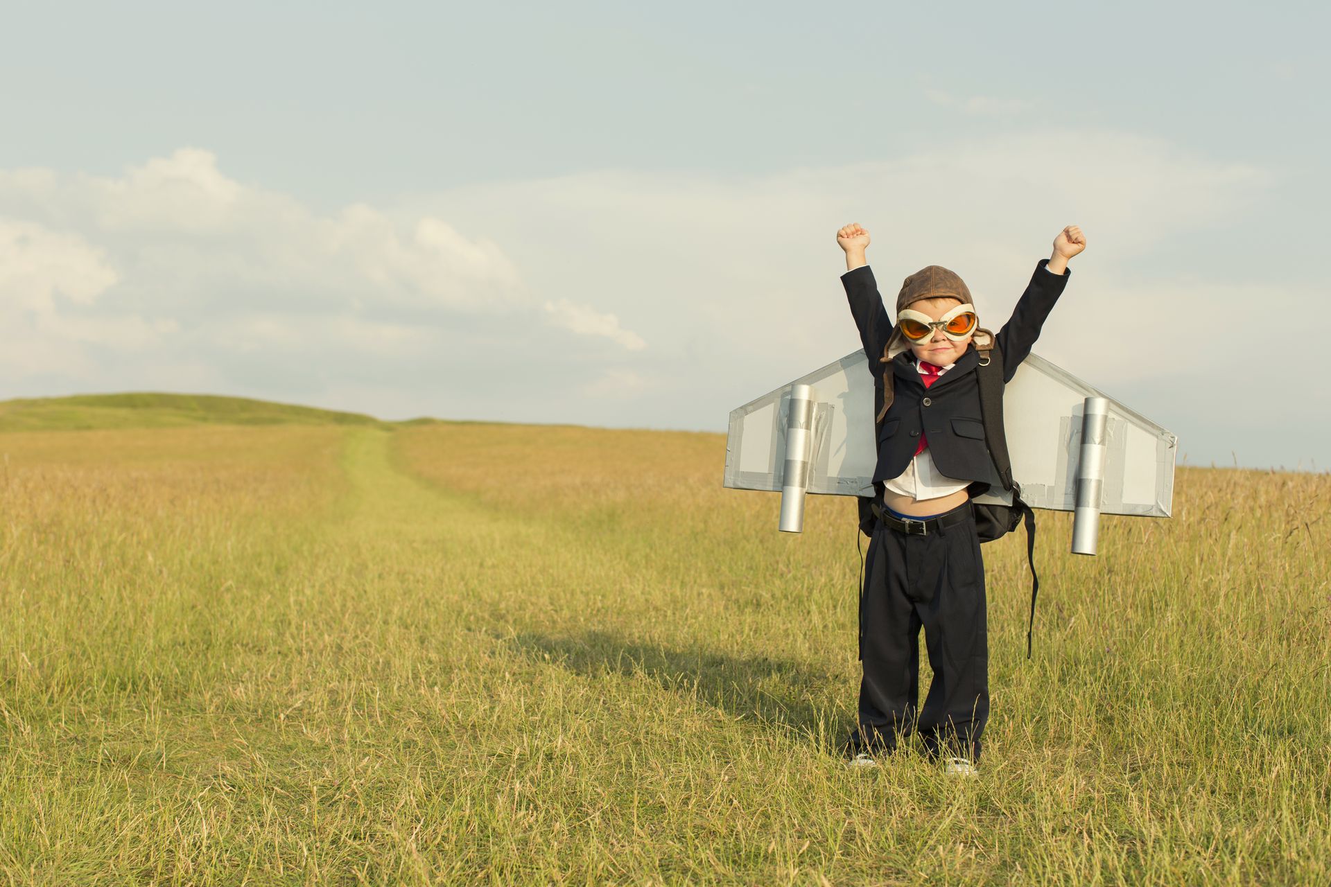 A child with home-made wings, arms to the sky